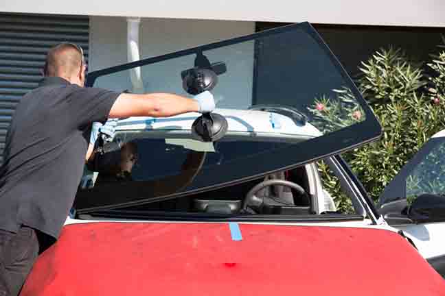 Windshield replacement, man is changing windscrenn on a car
